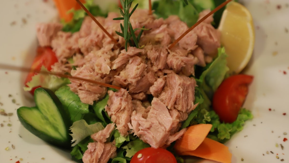 Close-up of a fresh tuna salad with vegetables and lemon garnish.