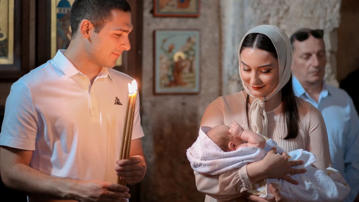 A peaceful baptism ceremony with family in a historical Orthodox church setting.