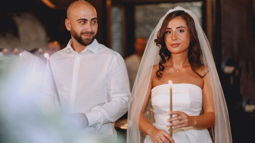 Bride and groom holding candles during a wedding ceremony indoors.