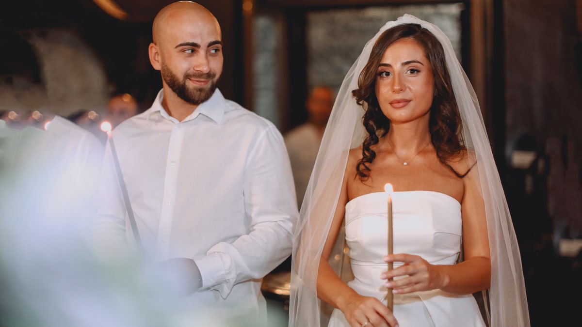 Bride and groom holding candles during a wedding ceremony indoors.